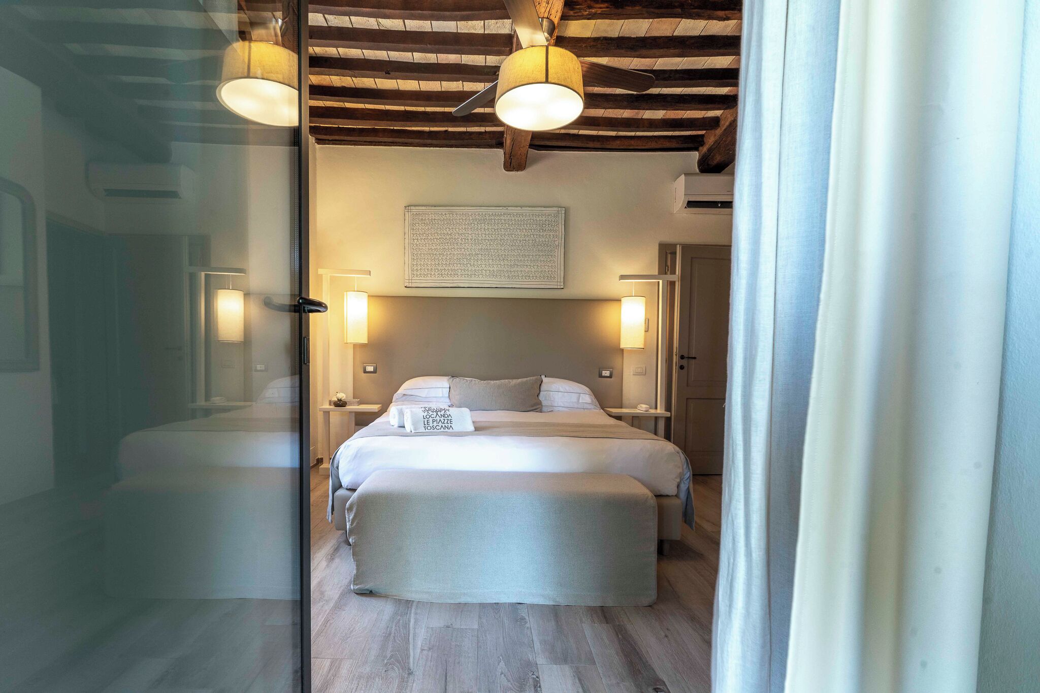 A bedroom with a bed, bedside lamps, a ceiling fan, and a wooden ceiling.