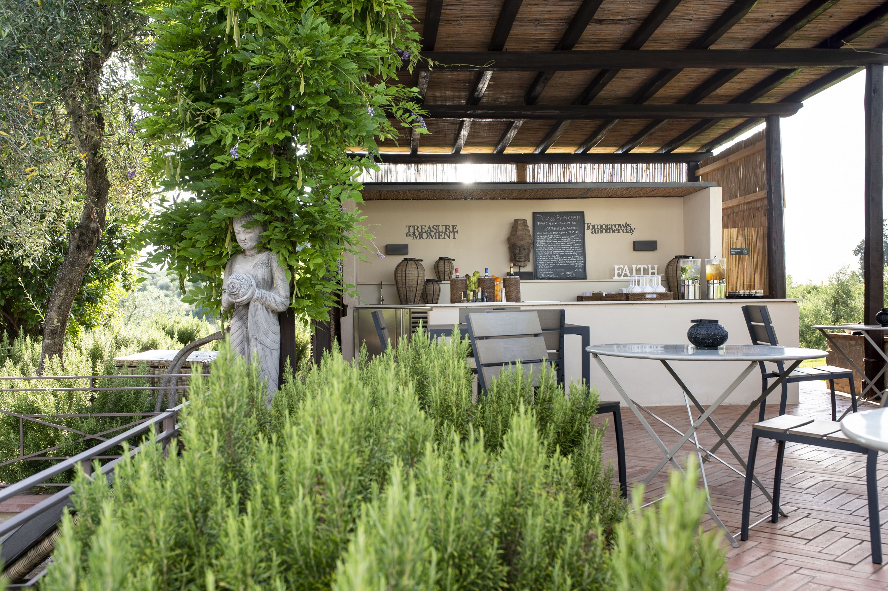 An outdoor seating area with tables and chairs, a statue, and a menu board.