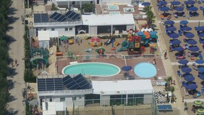 A rooftop pool area with multiple swimming pools, sun loungers, and a children's play area. - Residence Auriga (Rimini)