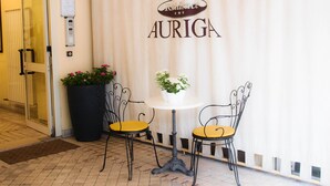 A hotel entrance with a curtain displaying the name "Auriga". There are two chairs and a table in front of the curtain. - Residence Auriga (Rimini)