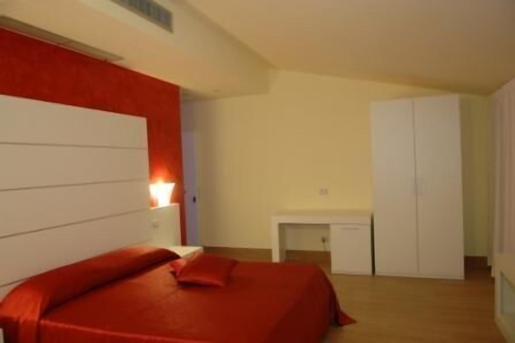 A bedroom with a bed, a bedside table, a desk, and a wardrobe.