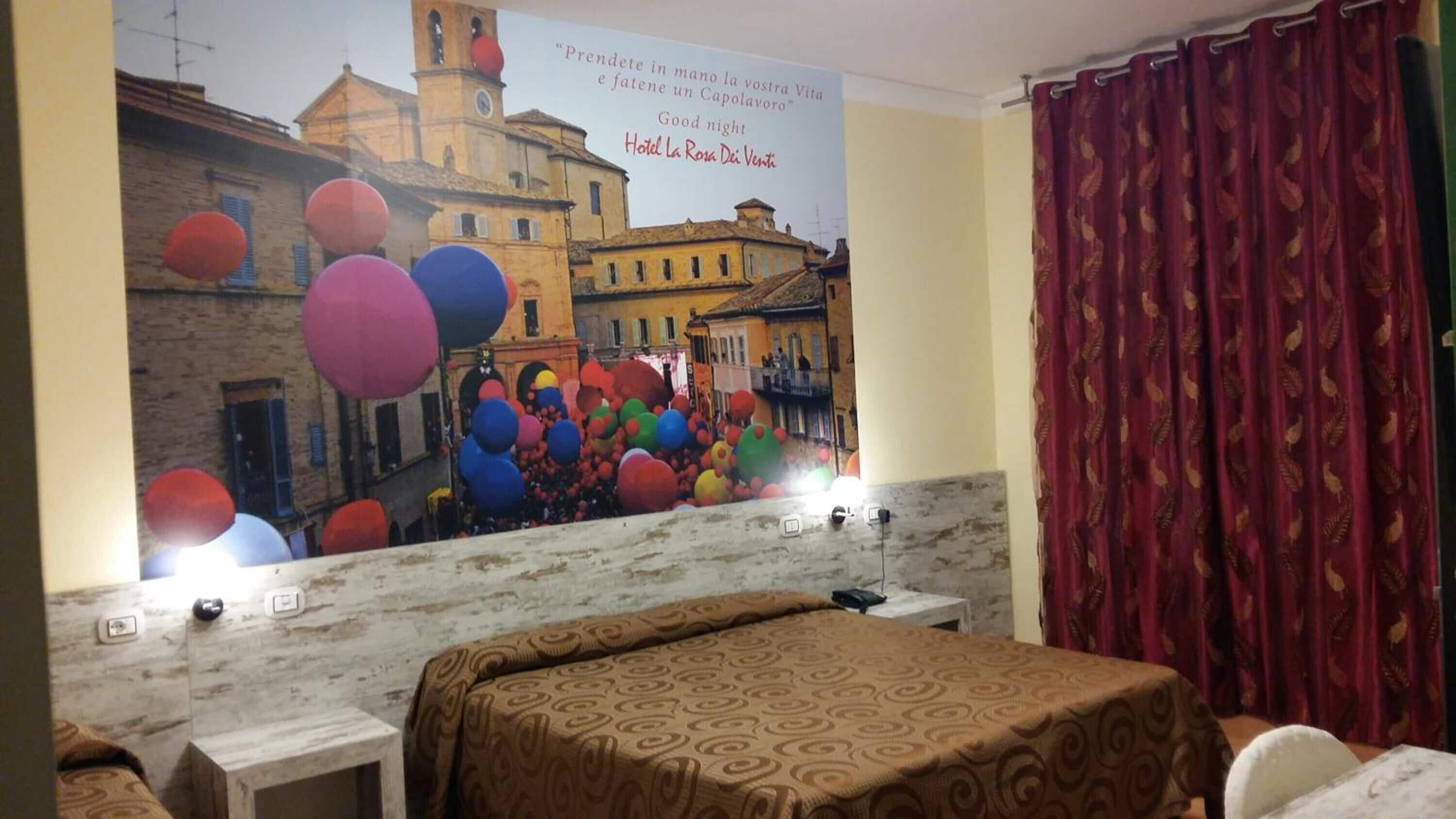 Una habitación de hotel con una cama, un escritorio y un cartel grande de una escena urbana.
