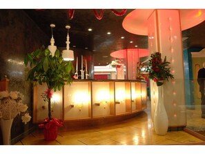 A reception area with a wooden reception desk, potted plants, and a glass partition. - La Rosa dei Venti (Monte San Giusto)