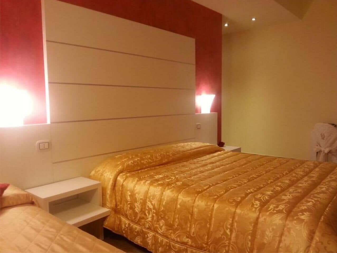 Una habitación de hotel con una cama grande, mesitas de noche y un cabecero.