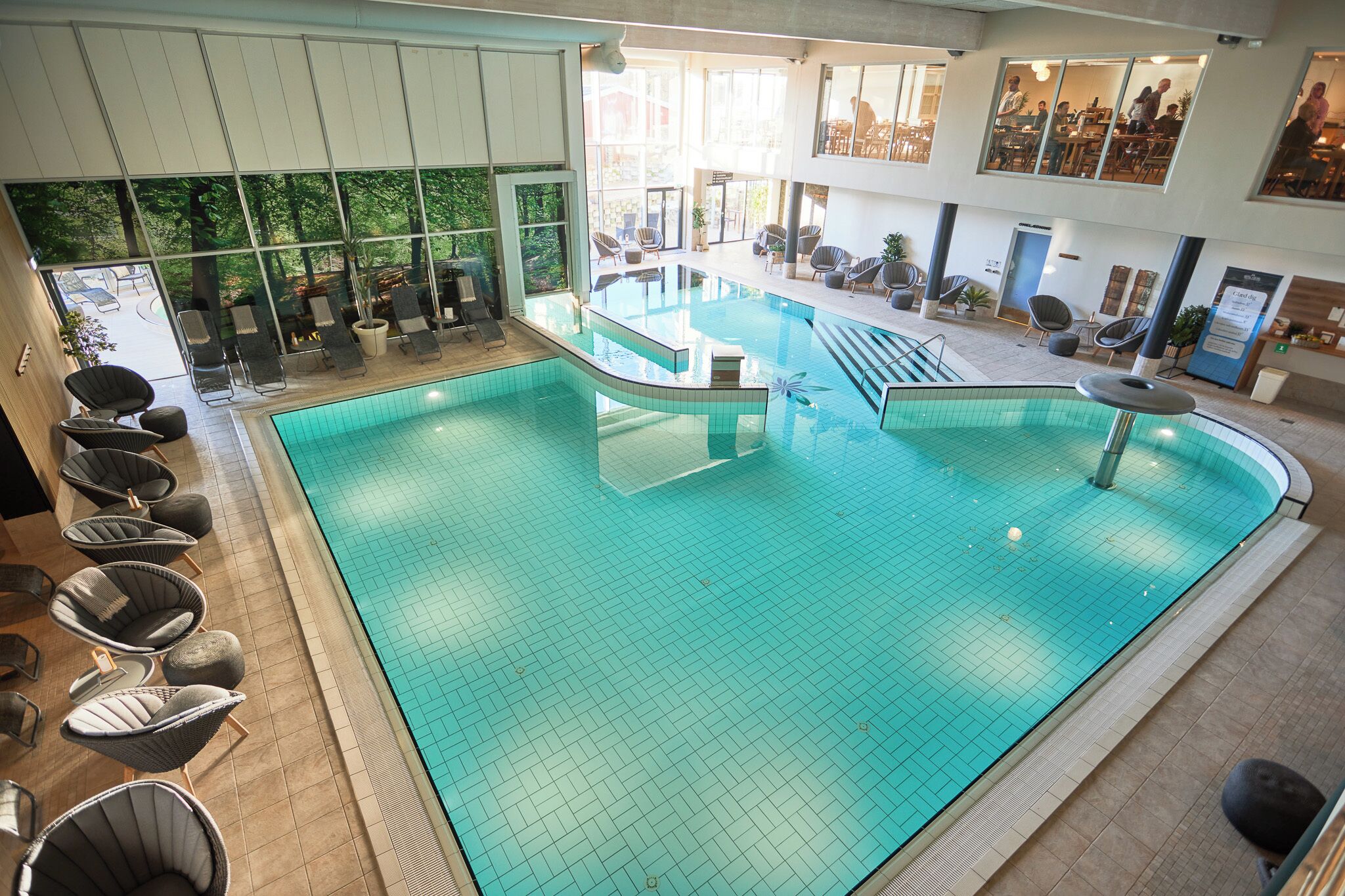 A large indoor swimming pool with lounge chairs and a seating area.
