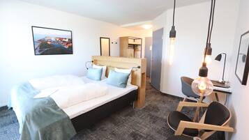 Een hotelkamer met een bed, een bureau, een stoel en een schilderij aan de muur.