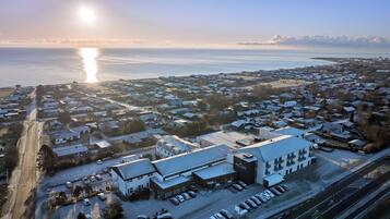 An aerial view of a coastal town with a prominent hotel named 'Hotel Viking' featuring a modern design, a parking lot, and a view of the sea.