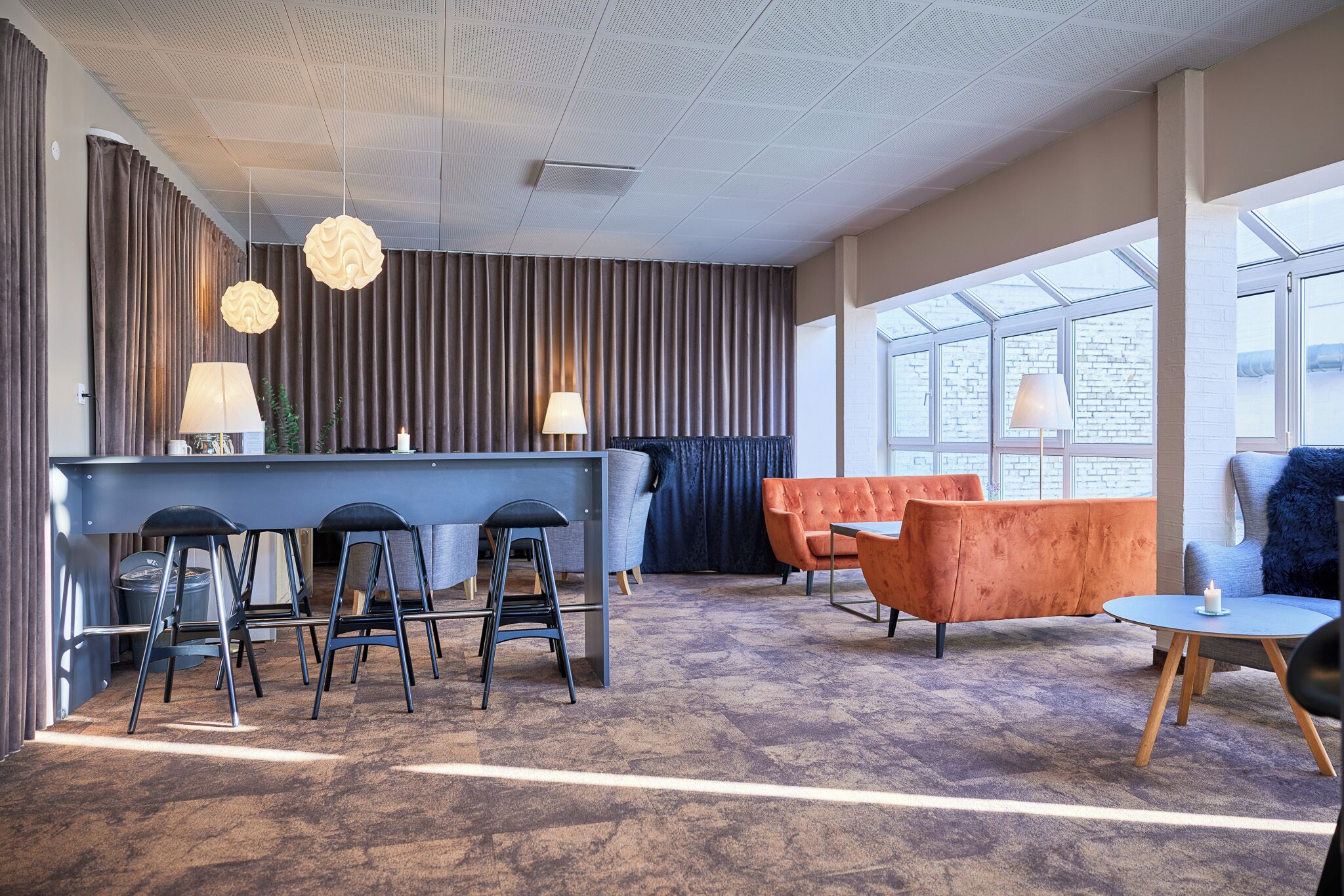 Un moderno vestíbulo de hotel con área de bar, asientos y ventanas amplias.