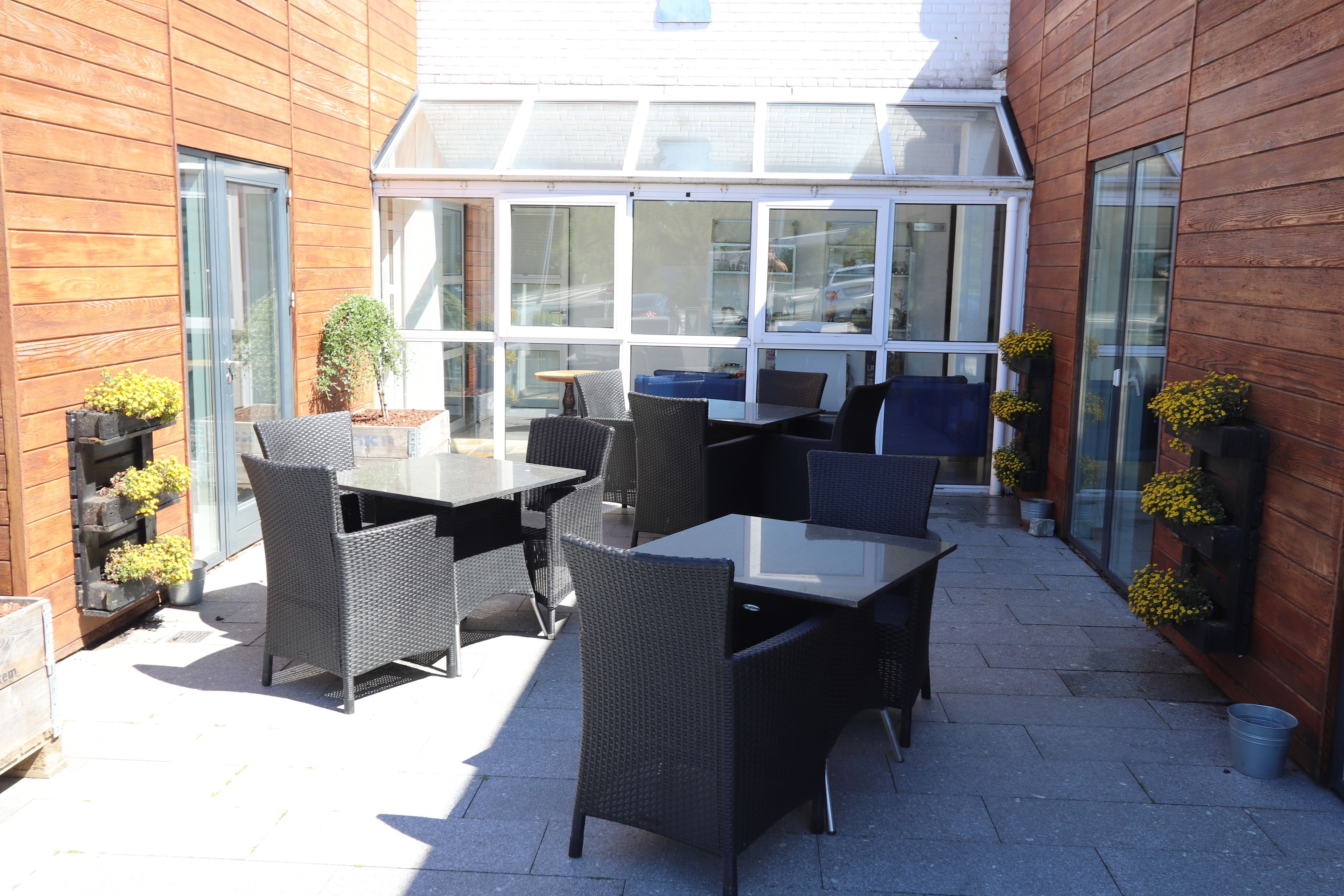 An outdoor patio with wicker furniture and potted plants.
