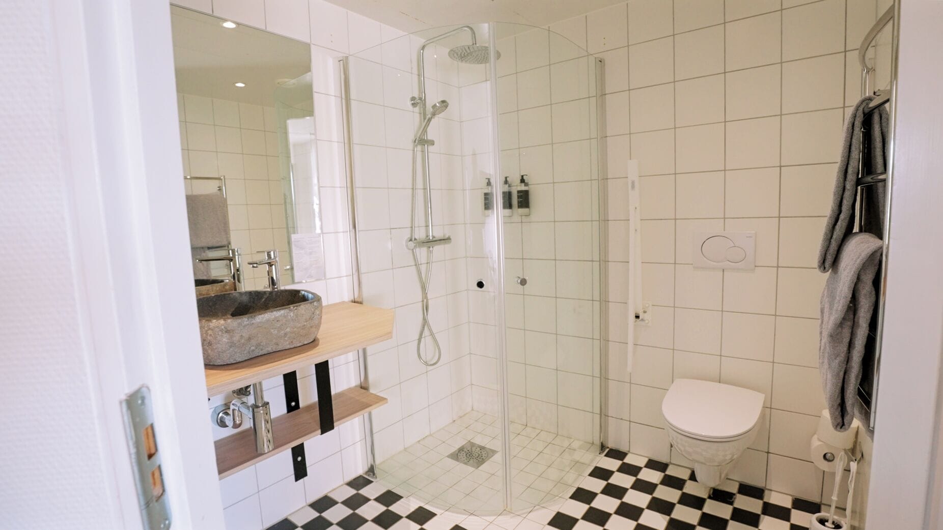 A modern bathroom with a stone sink, a glass-enclosed shower, and a toilet.