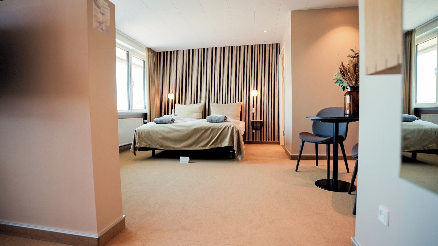 A modern hotel room with a bed, a desk, and a chair.