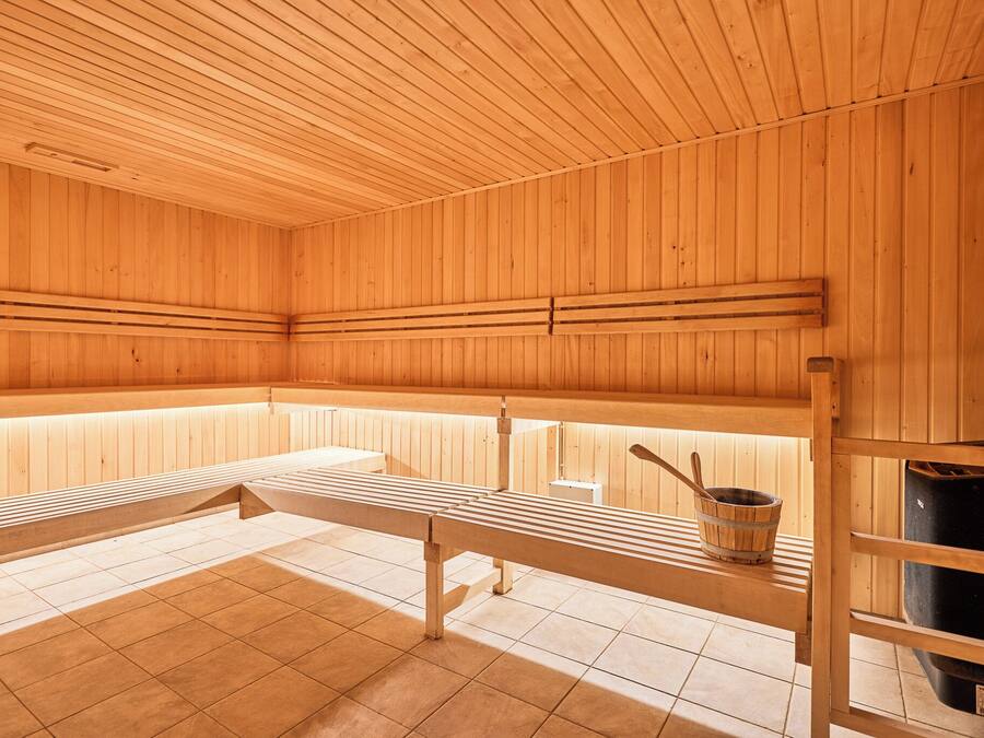 Un sauna avec des bancs en bois et un banc en bois avec un seau.
