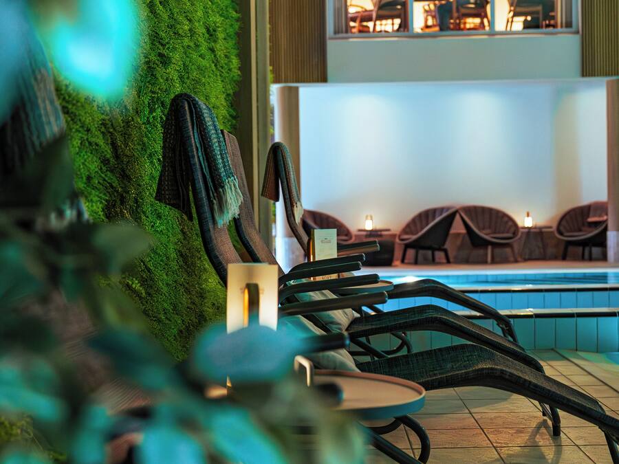 A poolside area with lounge chairs and a wall covered in green moss.