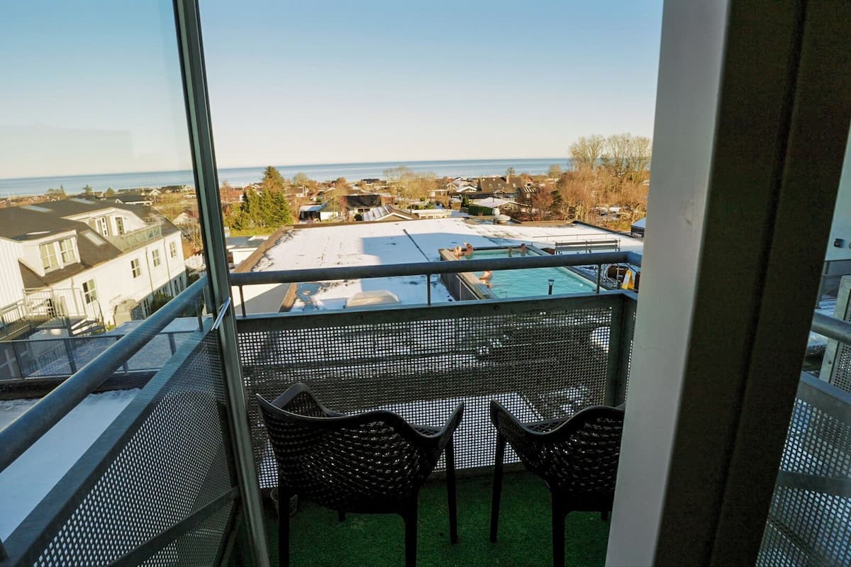 A balcony with a view of a residential area and a swimming pool.