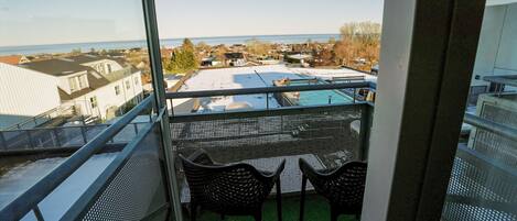 A balcony with a view of a residential area and a swimming pool.