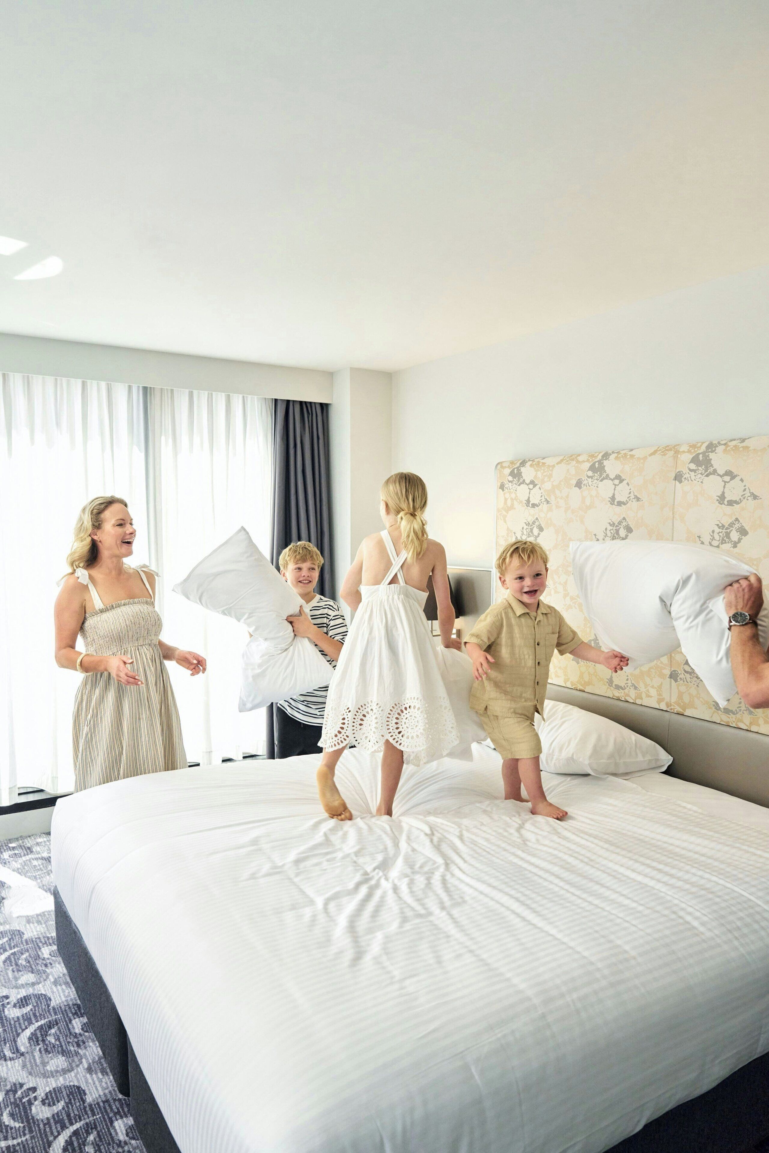 Een hotelkamer met een groot bed, een hoofdbord met bloemenmotief en een raam met gordijnen.