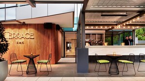 Un área de bar moderna con detalles de madera y sillas con cojines verdes.