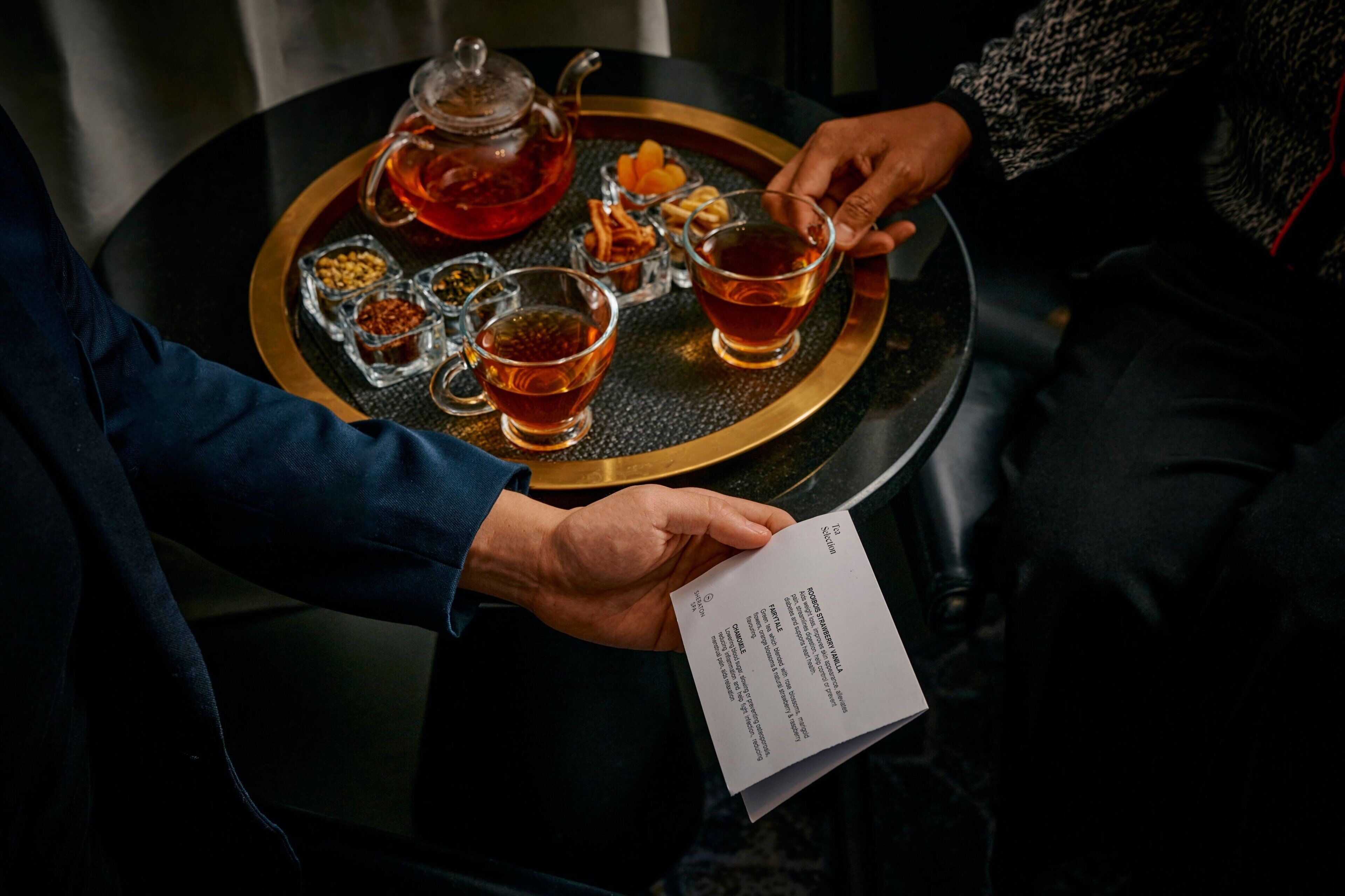 A tray with tea and snacks, a teapot, and a menu.