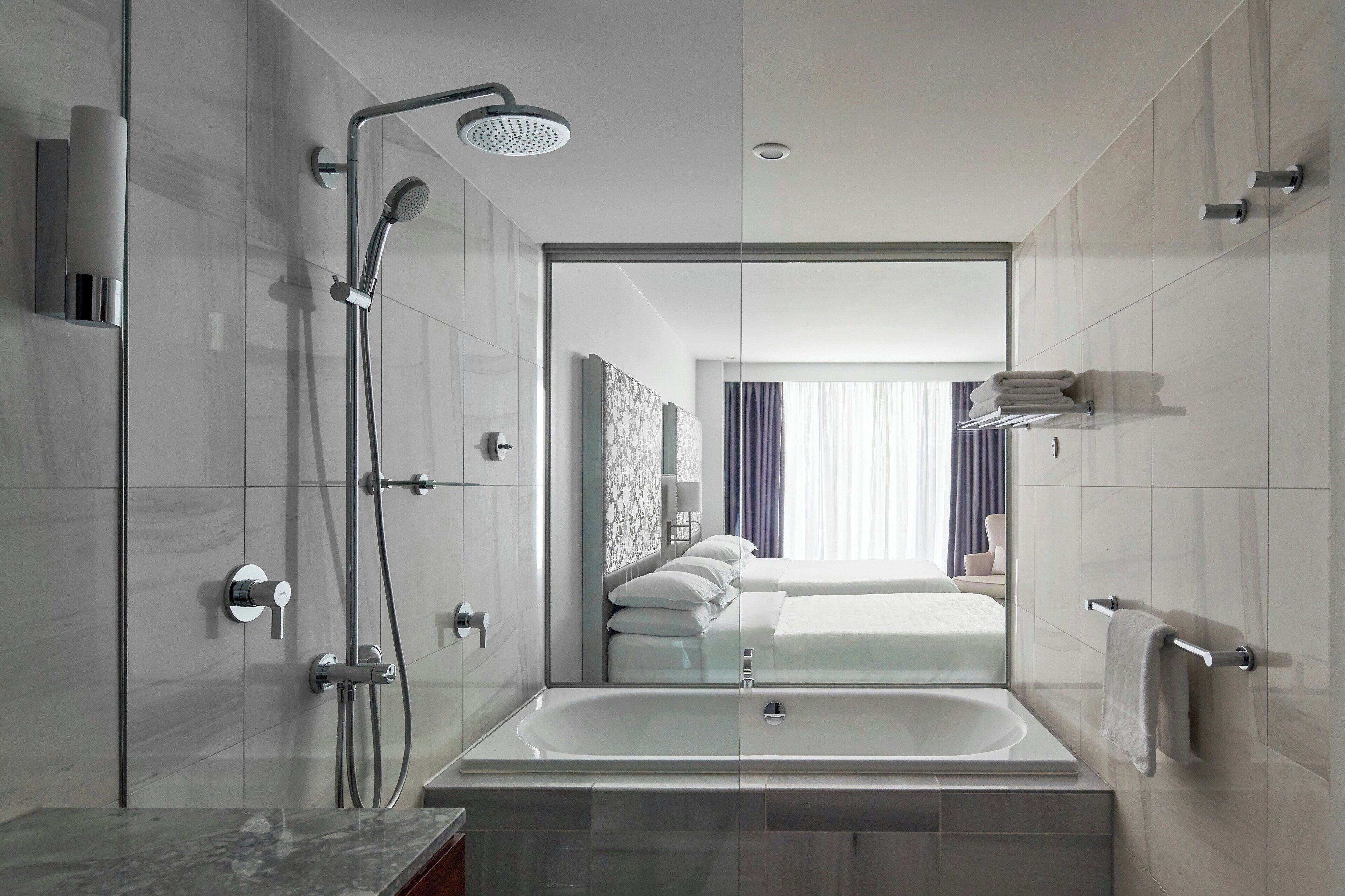 Un baño moderno con ducha, bañera y un dormitorio con paredes de vidrio.