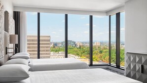 Habitación de hotel con dos camas, ventanas amplias y vista a la ciudad.