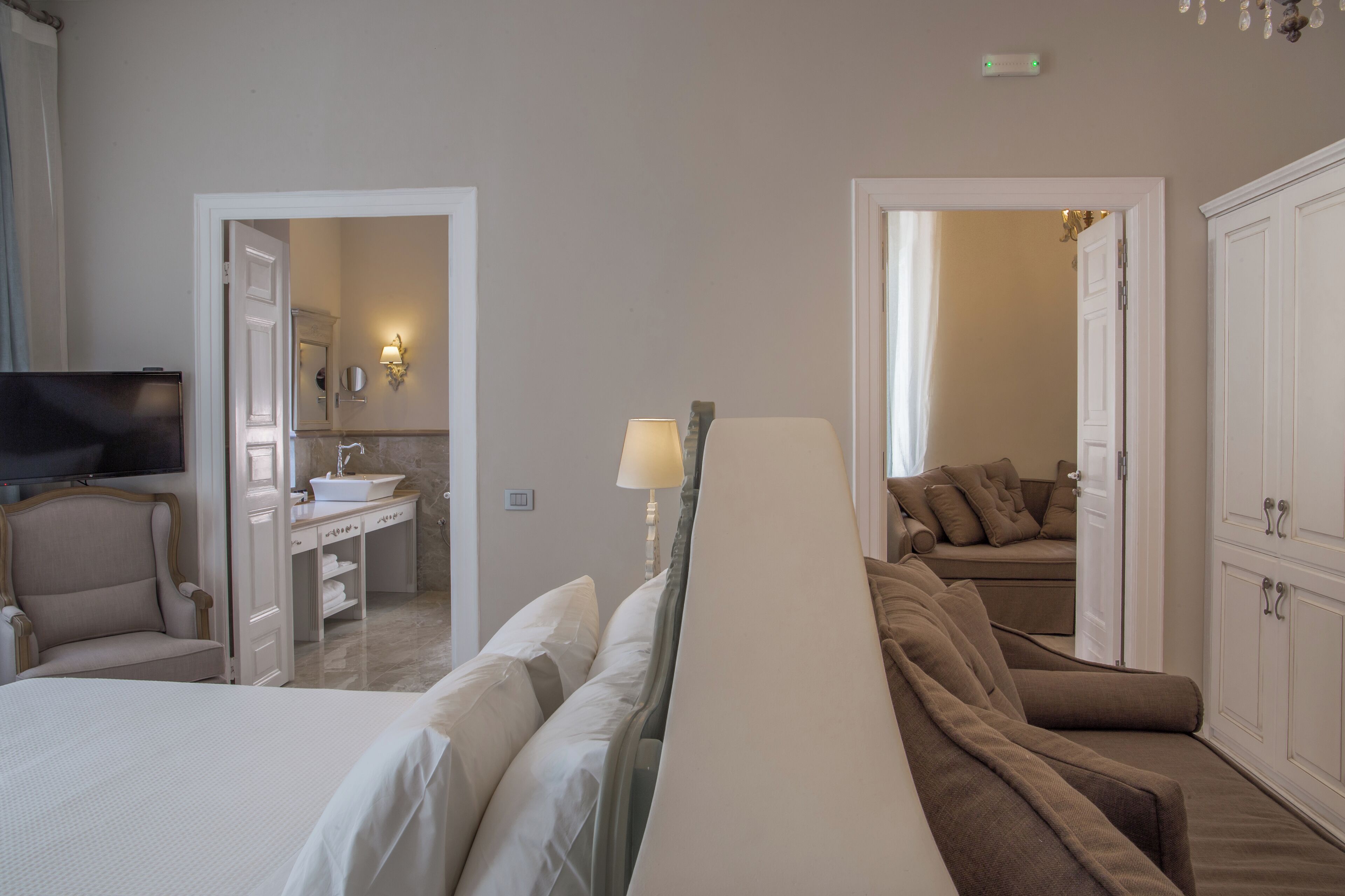 Ein Hotelzimmer mit Bett, Sofa, Fernseher, Badezimmer und Kleiderschrank.
