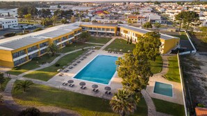 Vista aérea de um hotel com piscina, vários edifícios e paisagem ao redor.
