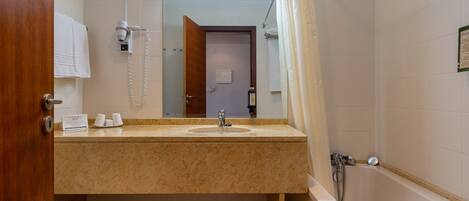 Une salle de bain équipée d’un lavabo, d’un miroir, d’une douche et de toilettes.