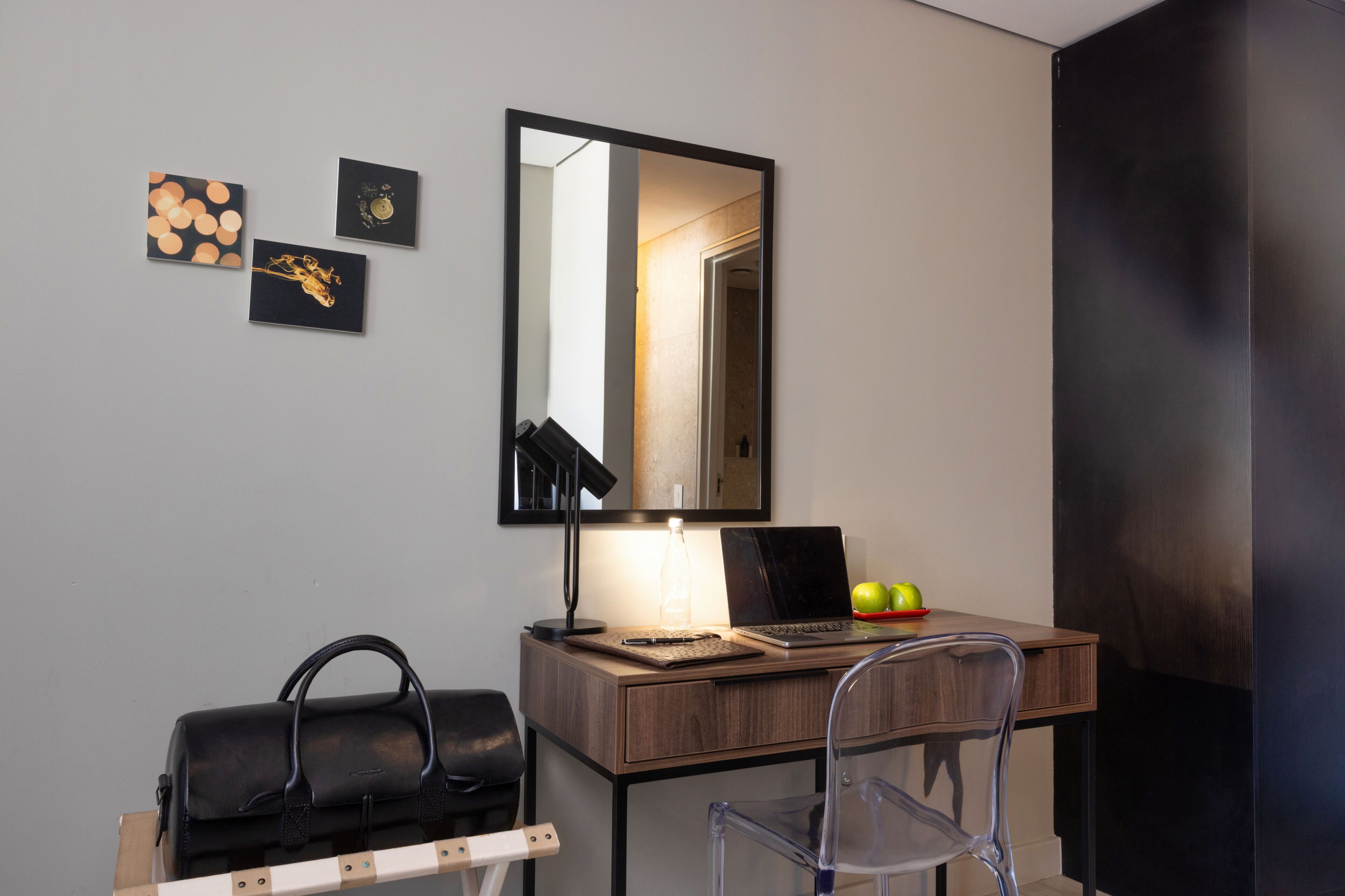 A room with a desk, chair, laptop, and a handbag.