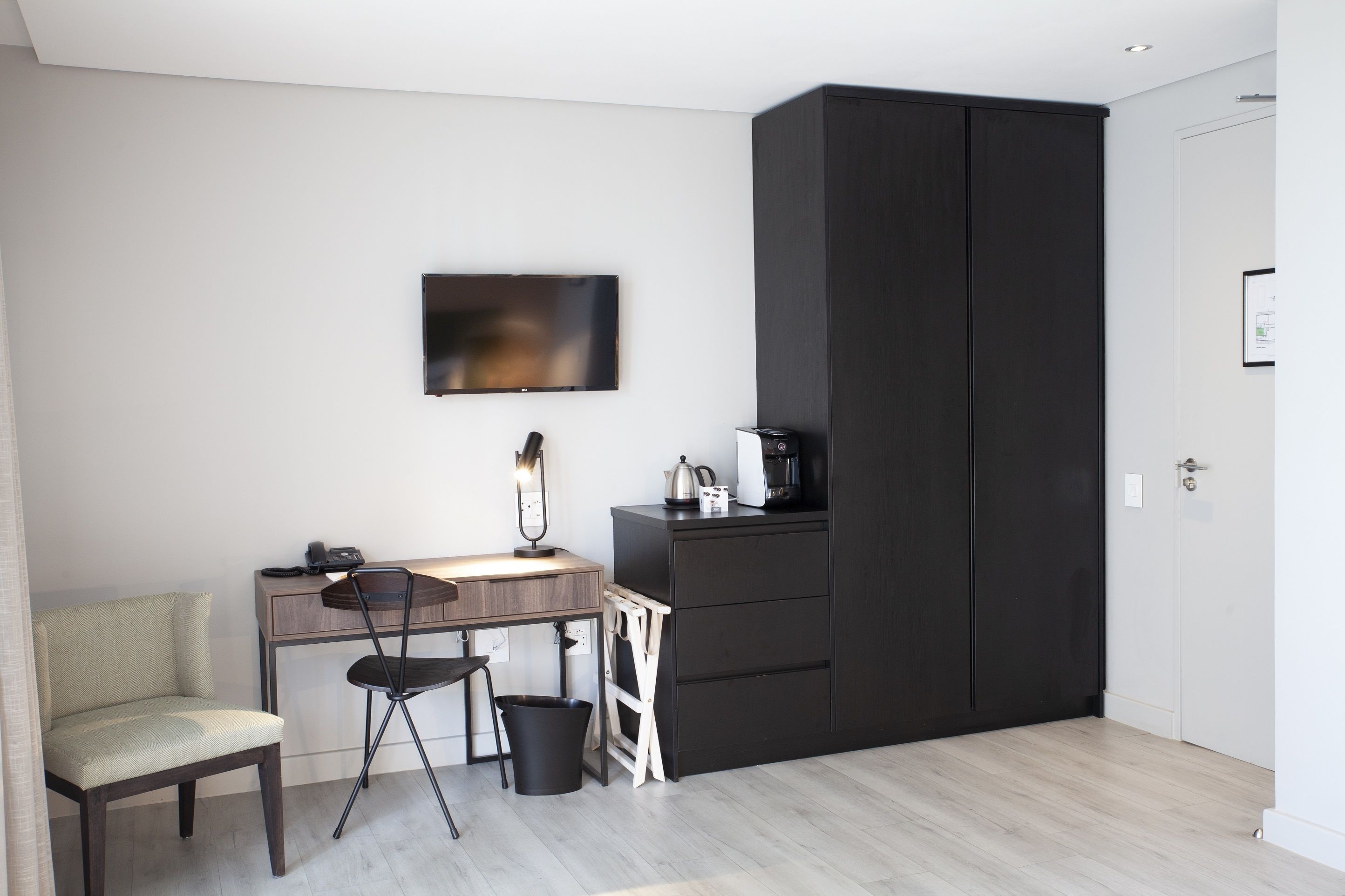 Ein modernes Zimmer mit Schreibtisch, Stuhl und großem Kleiderschrank.
