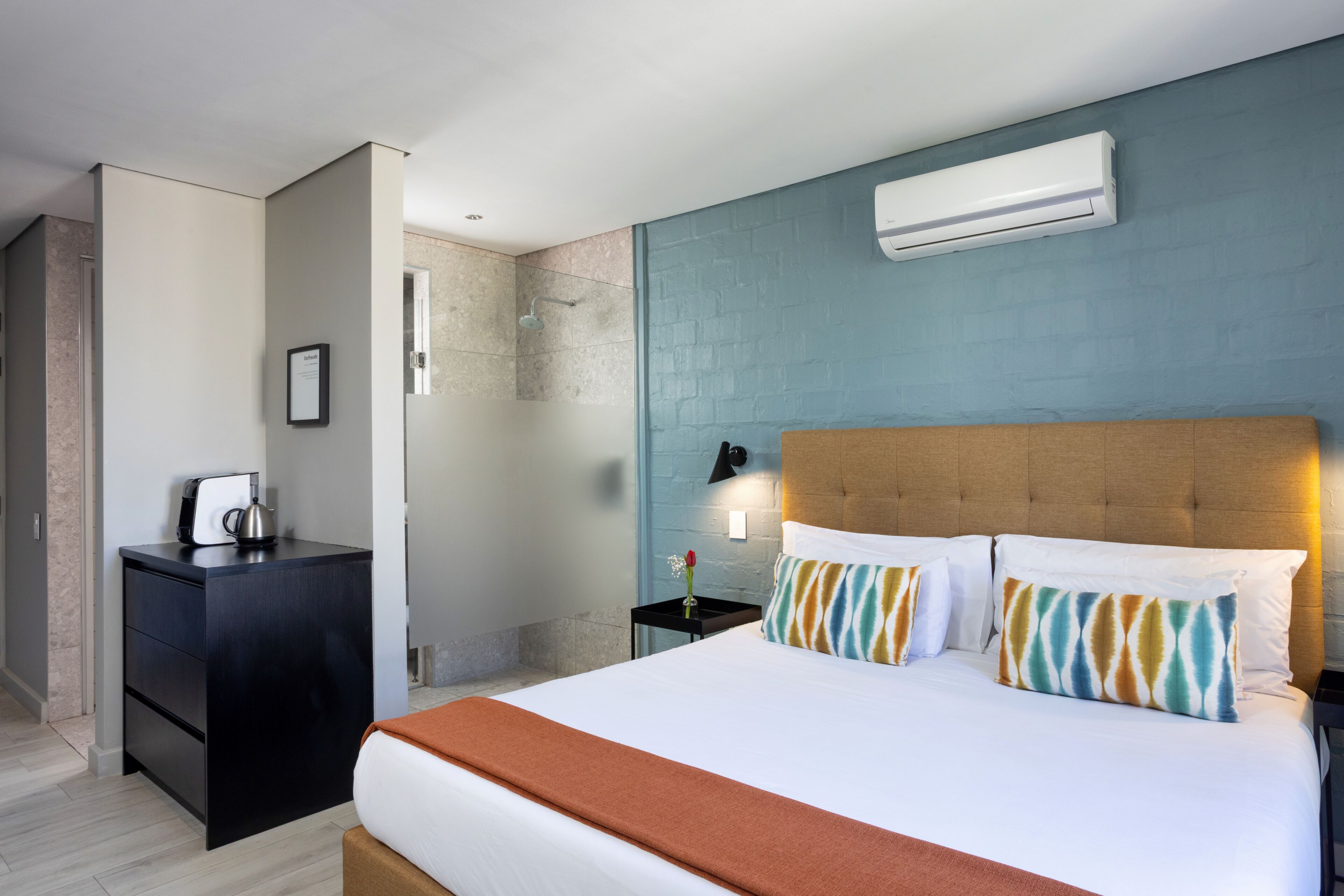 Une chambre d’hôtel équipée d’un lit, d’une table de chevet, d’une commode et d’un appareil de climatisation.