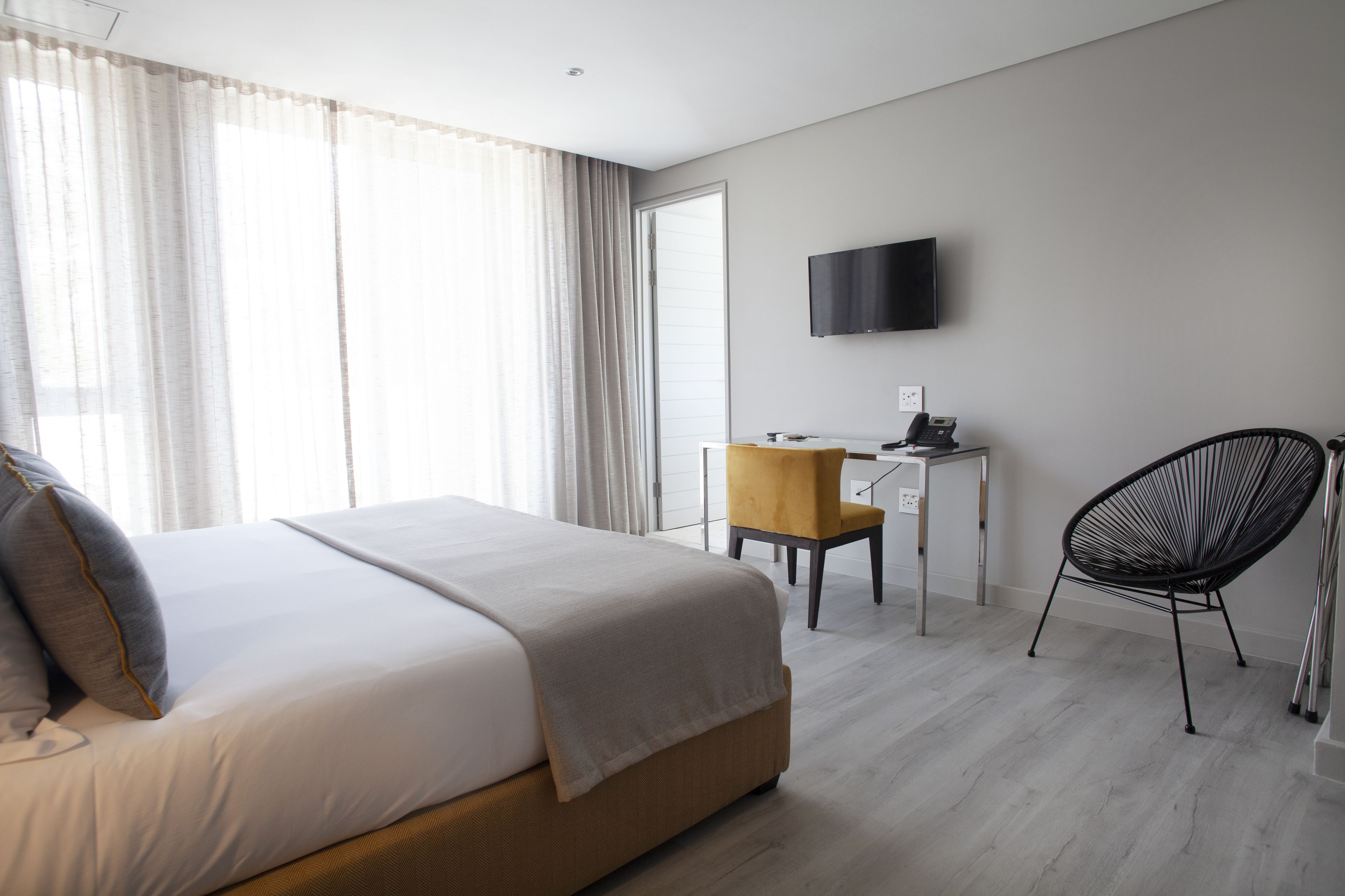 A hotel room with a bed, a desk, a chair, and a TV on the wall.
