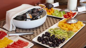 A breakfast buffet with various fruits, yogurt, and a bowl of chocolate spreads.