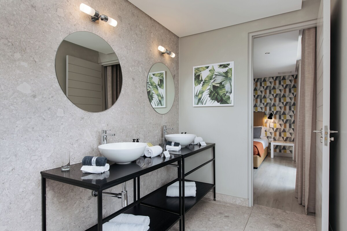 A modern bathroom with a double sink vanity, two mirrors, and a towel rack.