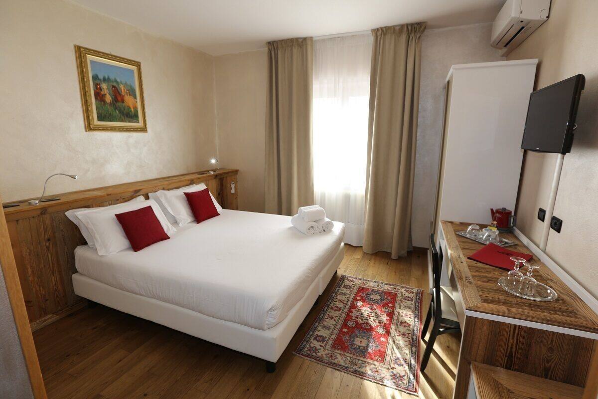 A hotel room with a bed, a desk, a TV, and a window with curtains.