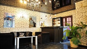 Eine Lobby mit schwarzem Marmorboden, einem Empfangstresen, einer Kandelaber und einer großen Topfpflanze.