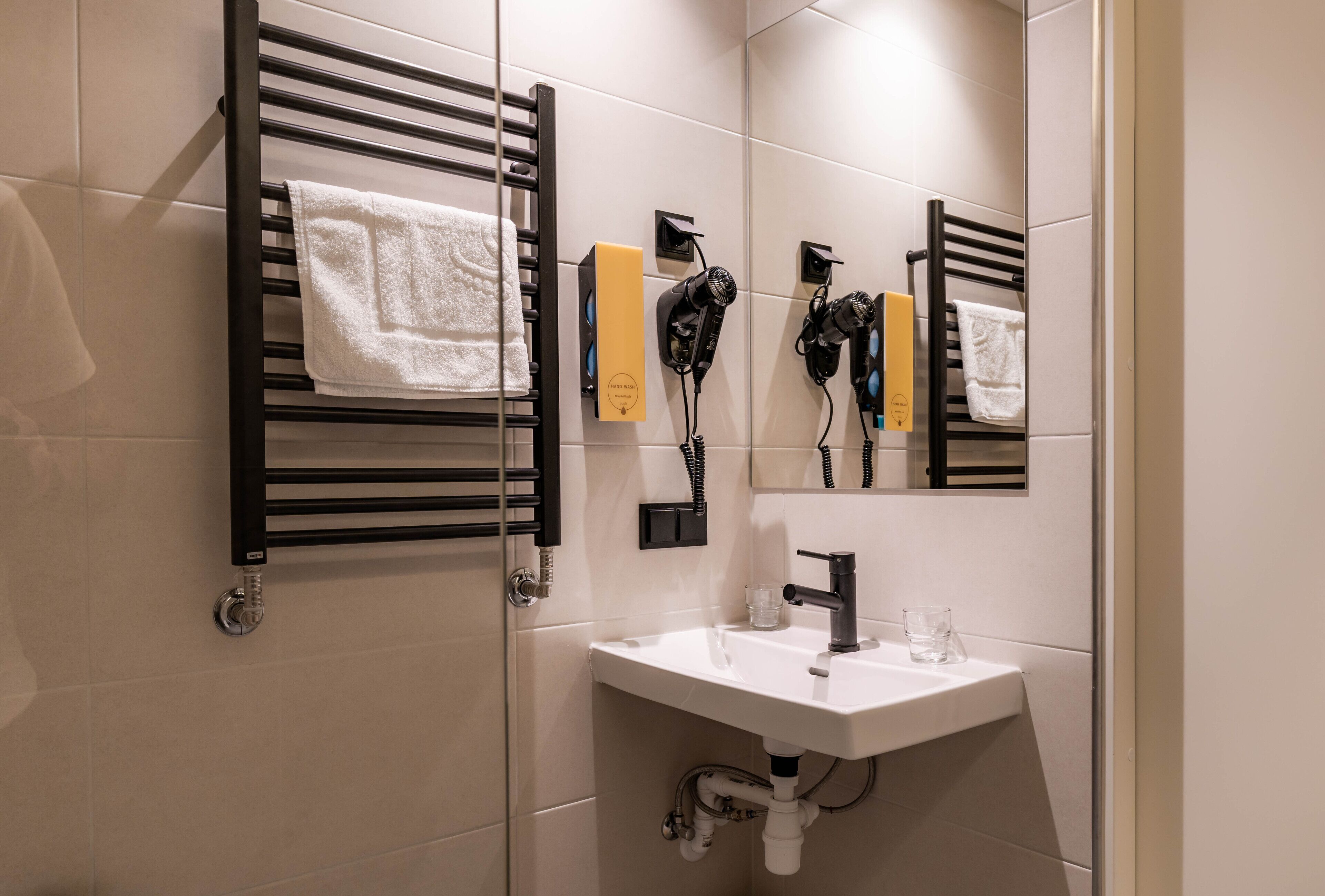 A modern bathroom with a black towel rack, a white sink, and a mirror.