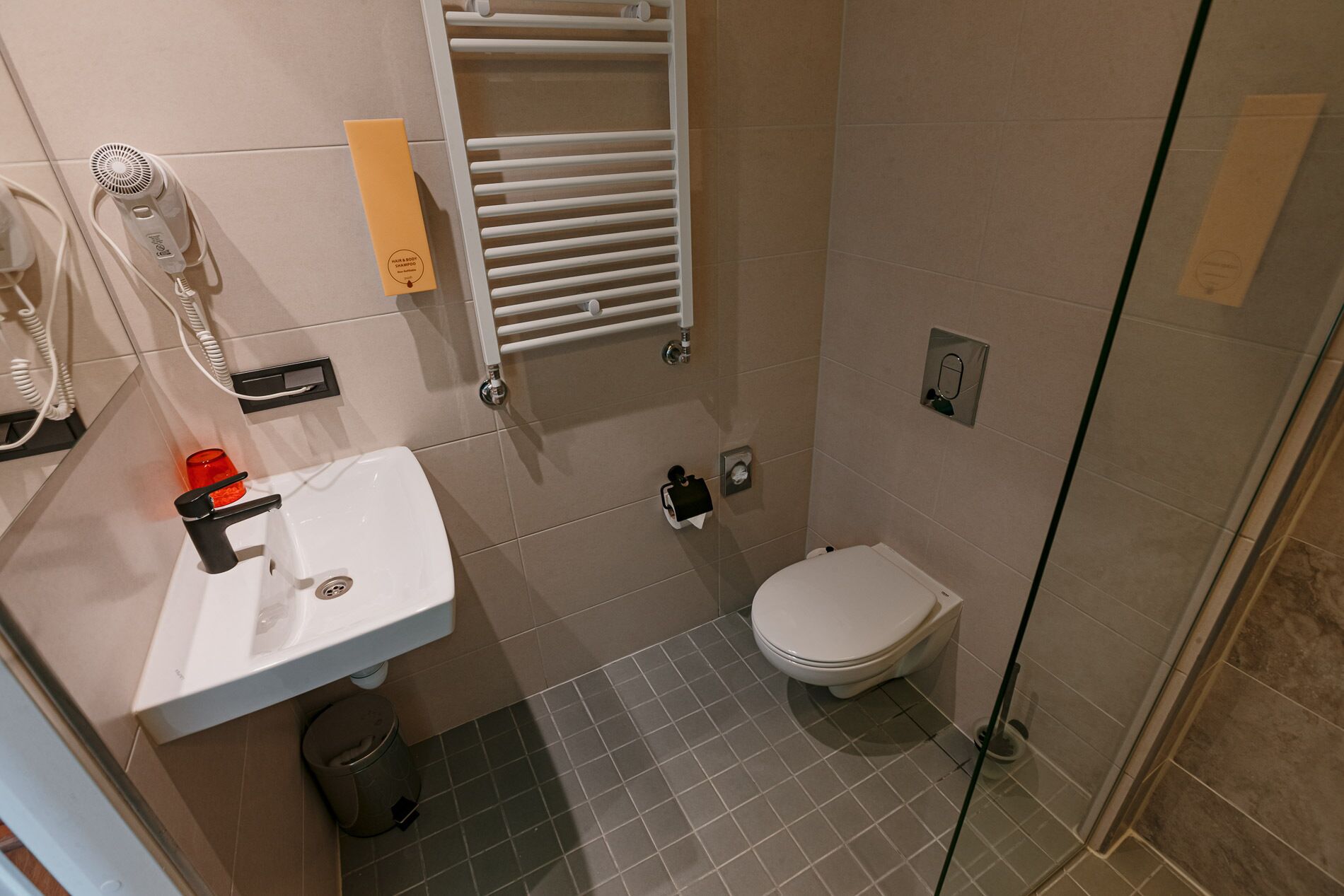 Een moderne badkamer met een wit wastafelmeubel, een toilet en een douchecabine met glazen wanden.