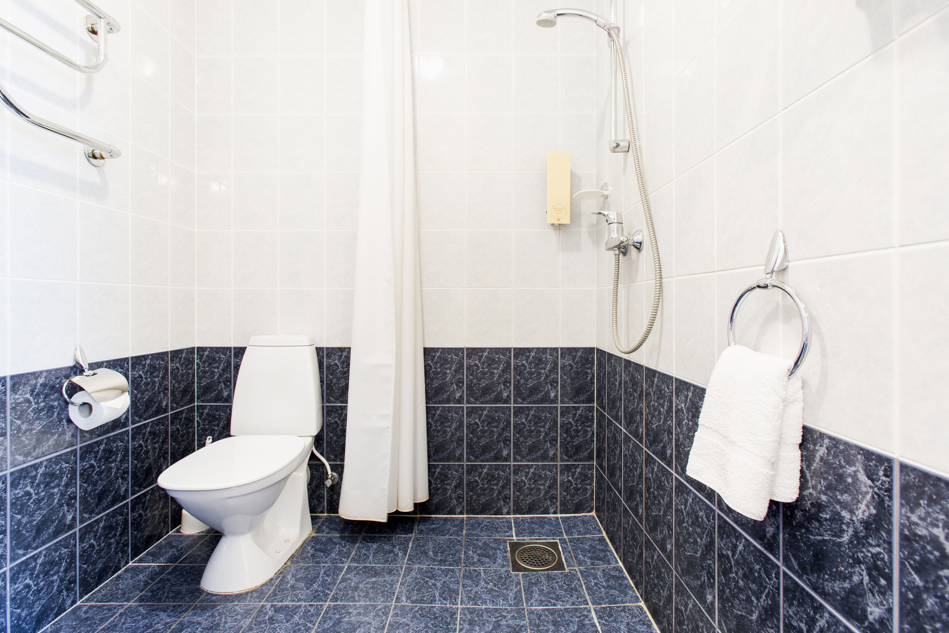 A bathroom with a toilet, shower, and towel rack.