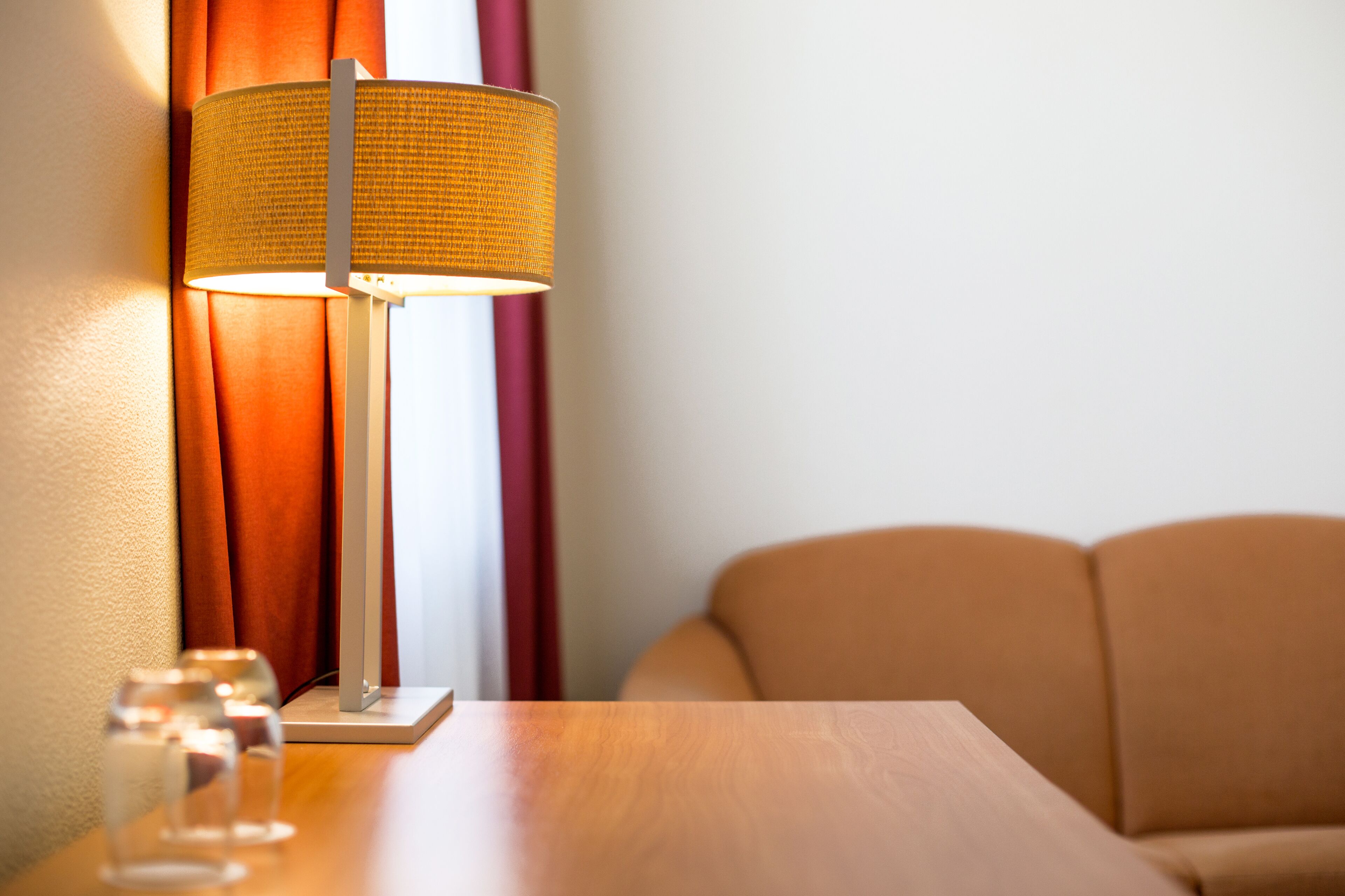 A room with a wooden table, a lamp, and a sofa.