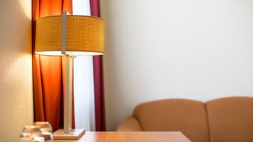 A room with a wooden table, a lamp, and a sofa.