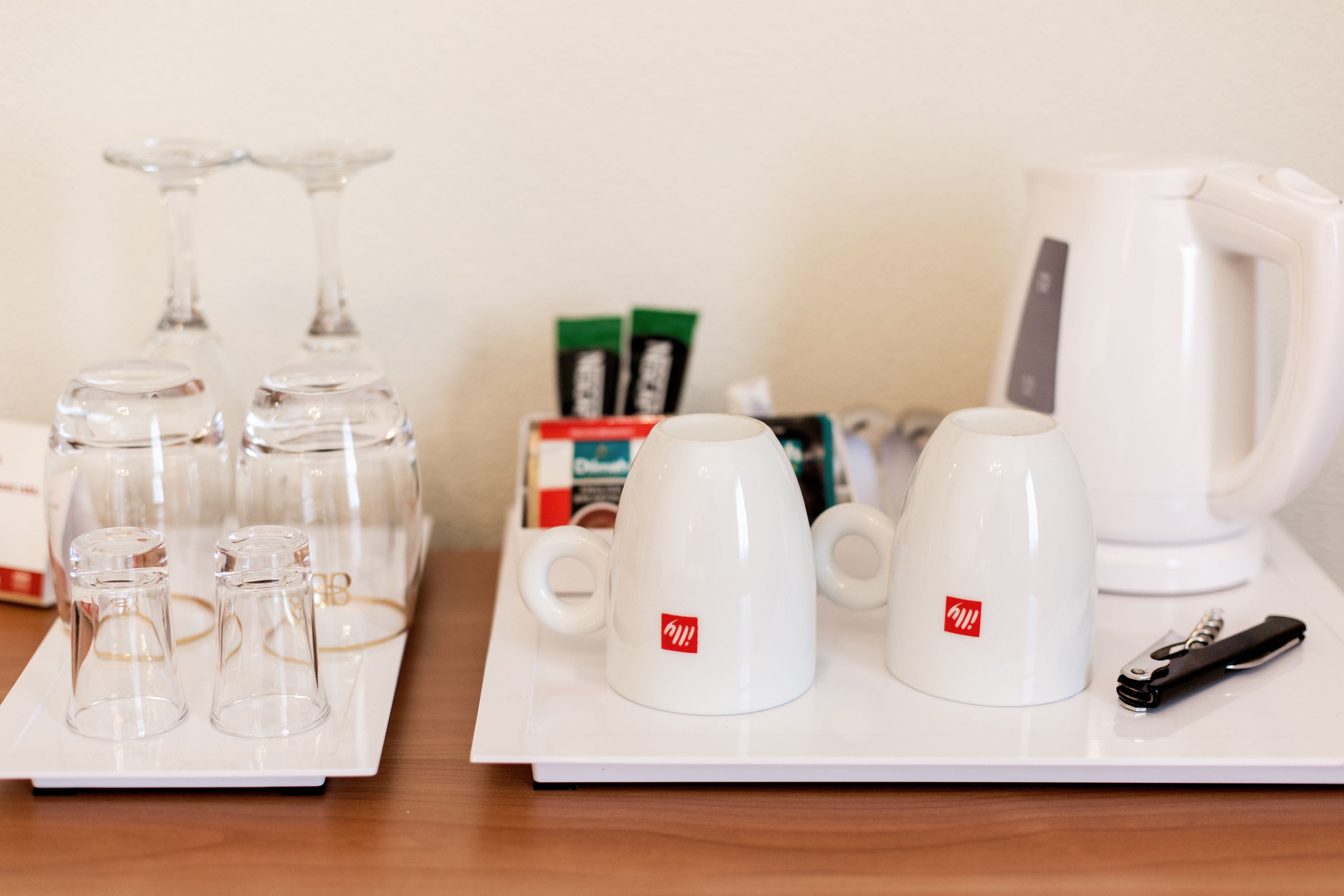 A tray with coffee cups, a coffee pot, a bottle opener, and a box of coffee creamer.