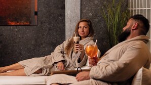 A couple relaxing in a modern spa room with a wooden ceiling, a large plant, and a textured wall. - Narva Hotell & Spa (Narva)