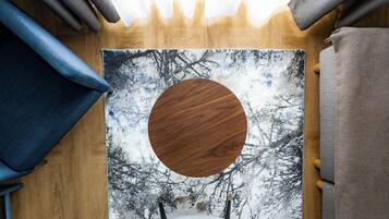 A room with a wooden floor, a large painting of trees, a circular wooden object, and a blue and brown curtain.