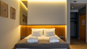 A hotel room with a large bed, wooden headboard, and a mirror above it. There are two bedside tables and a small nightstand. - Narva Hotell & Spa (Narva)