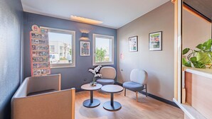 A modern lounge area with seating, a small table, and decorative elements. - B&B HOTEL Strasbourg Aéroport (Holtzheim)