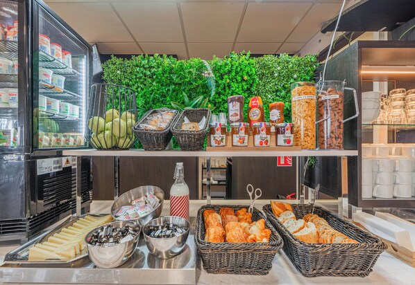 Un bufé de desayuno con diversas opciones de comida, incluyendo pan, bollería y salsas.