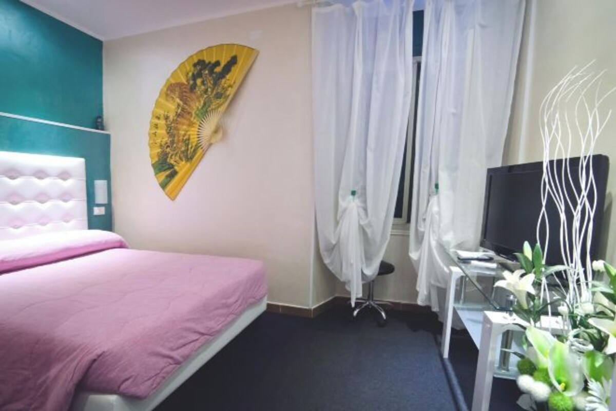 A hotel room with a bed, a TV, a desk, and a chair.