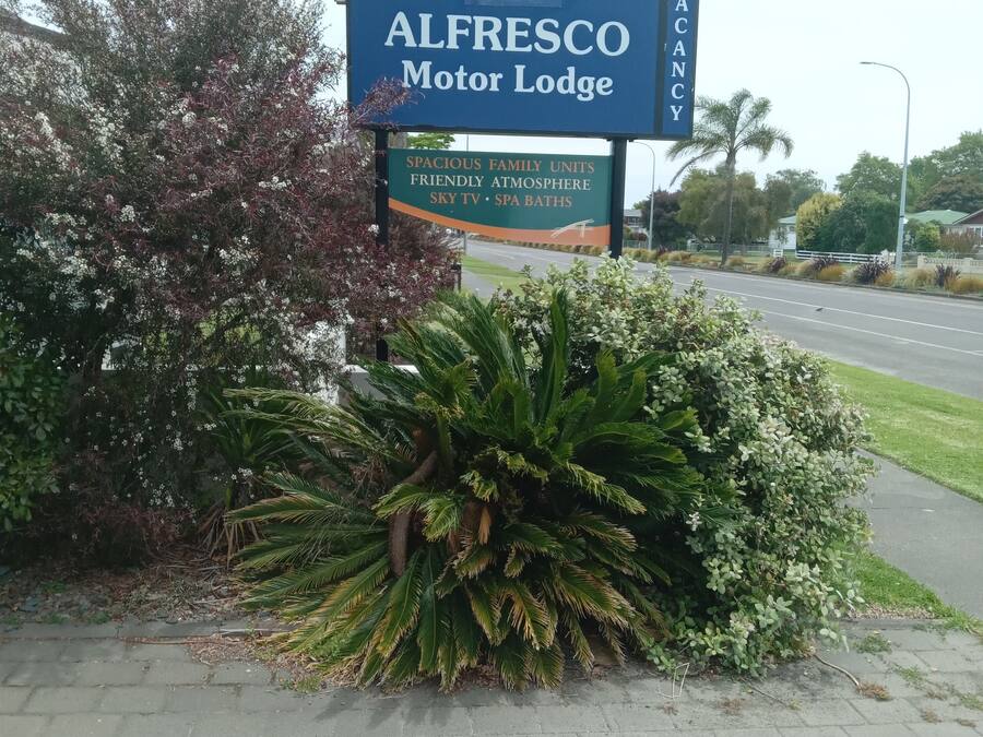Schild des Alfresco Motor Lodge, das geräumige Familienzimmer, eine freundliche Atmosphäre, Sky TV und Whirlpools bewirbt.