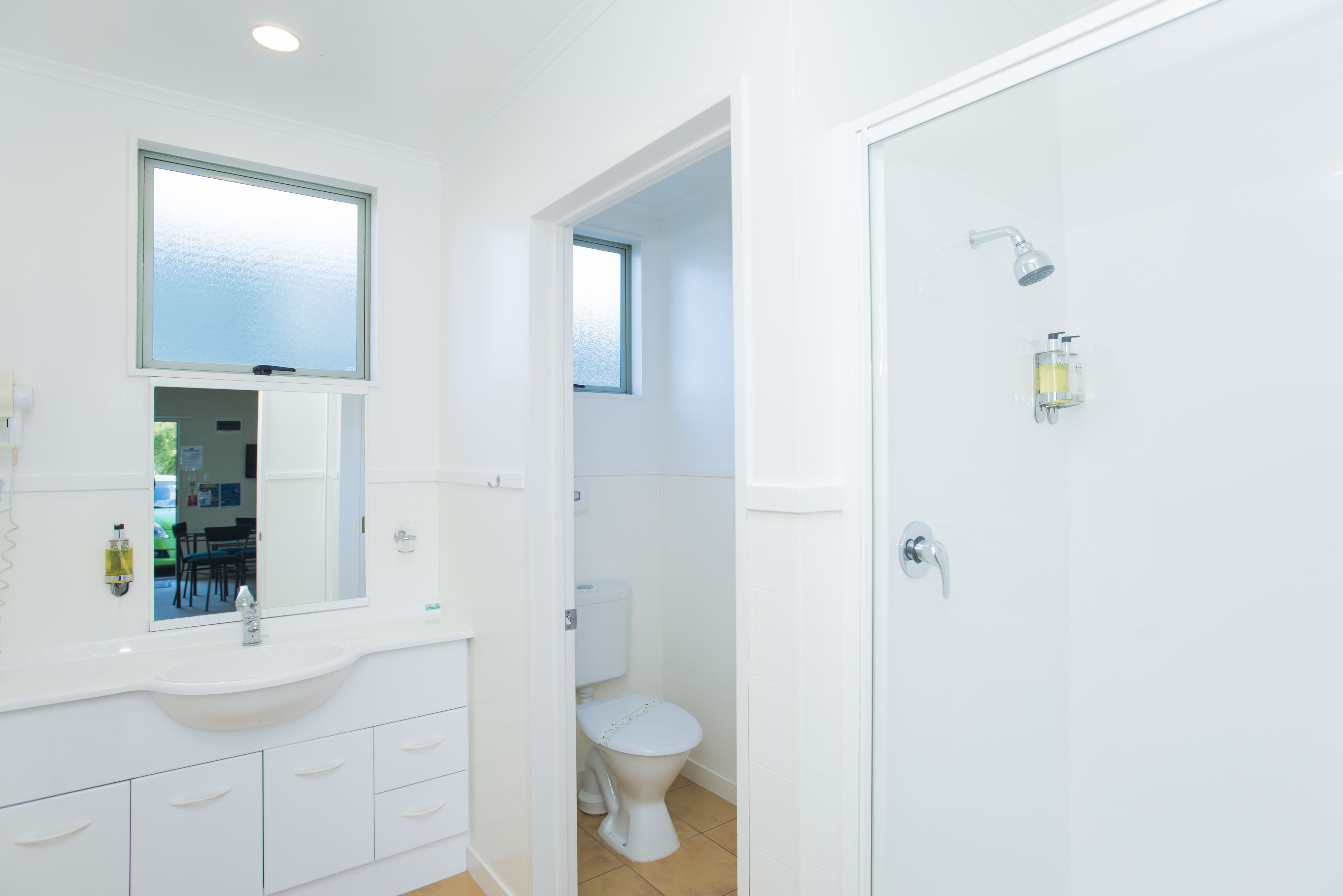A modern bathroom with a sink, mirror, toilet, and shower.