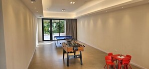 A spacious room with a foosball table, a ping pong table, and a dining area with red chairs. - Hotel Argentina (Atlantida)